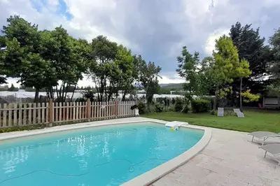 a swimming pool with two chairs and a fence at Chambre d'Hotes Manon - Domaine Les Peupliers - in Lagnes