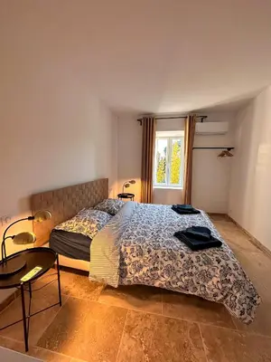 a bedroom with a bed and a table and a window at L'appart des Anges in Althen-des-Paluds