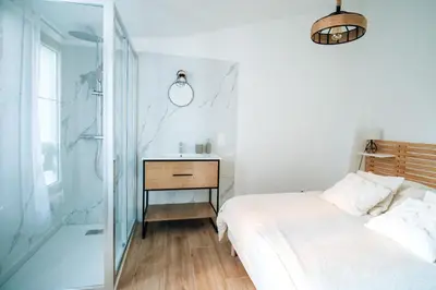 a bedroom with a bed and a glass shower at Le constantinou in Saint-Michel-lʼObservatoire