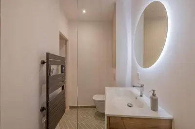 a white bathroom with a sink and a mirror at Appartement de charme in Aix-en-Provence