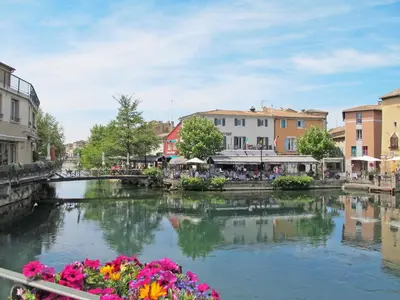 a river in a town with a bridge and flowers at Villa Le Bouloulou by Interhome in Velleron