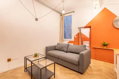 a living room with a couch and an orange wall at Charmant T2 centre in Aix-en-Provence