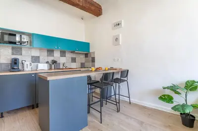 a kitchen with blue cabinets and a counter with stools at Studio place cardeurs in Aix-en-Provence