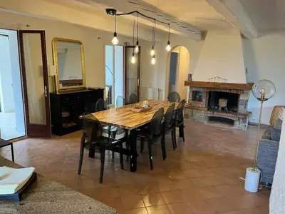 a dining room with a table and chairs and a fireplace at Jolie maison avec vue imprenable, piscine, jeu de boules, calme au cœur du Luberon in Les Cordiers