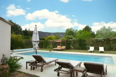 a swimming pool with two chairs and an umbrella at Souleia in Oppède