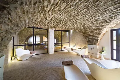 a room with white chairs and a stone wall at Moulin de Vernègues Hôtel & Spa in Mallemort