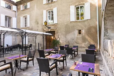a patio with tables and chairs in front of a building at Moulin de Vernègues Hôtel & Spa in Mallemort