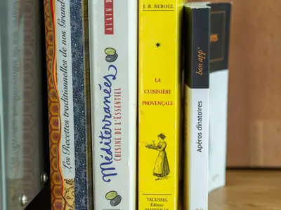 a row of books sitting on a shelf at l'Instant Parfait in Aix-en-Provence