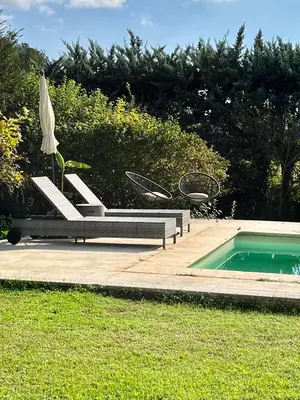 a pool with a chair and an umbrella next to a pool at Charmante maisonnette avec jardin et piscine in Aix-en-Provence