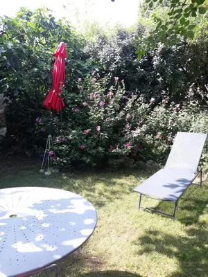 a table and a chair and a red umbrella at La maison du jardin in Rustrel