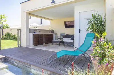 a patio with a blue chair on a wooden deck at Maison des Fleurs in Vedène