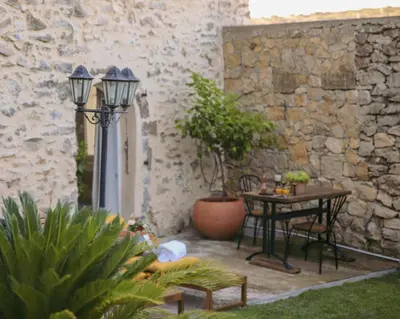a patio with a table and chairs and a stone wall at Unique guest room in the heart of Provence 