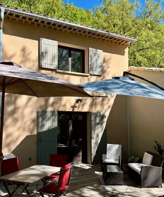 a patio with a table and an umbrella and chairs at Gîte Nature en Luberon in Céreste
