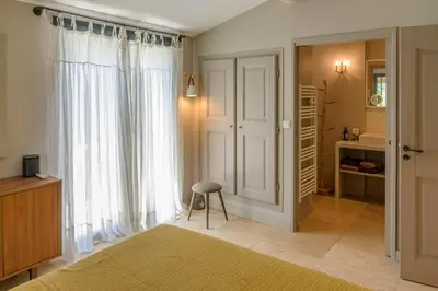 a bedroom with a window and a stool in a room at Bastide Blanche Villa with swimming pool and pétanque court in Lourmarin in Lourmarin
