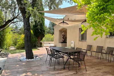 a patio with a table and chairs under a tree at Villa Maya Large villa and amazing pool in Luberon in Puget