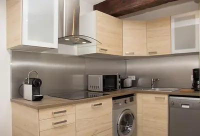 a kitchen with wooden cabinets and a washer and dryer at Gîte les iris in LʼIsle-sur-la-Sorgue