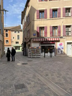 a couple of people walking down a street next to a building at Gîte les iris in LʼIsle-sur-la-Sorgue