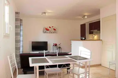 a living room with a table and chairs and a kitchen at Gîte les coquelicots 2 Quartier résidentiel ( 2 * ) in LʼIsle-sur-la-Sorgue