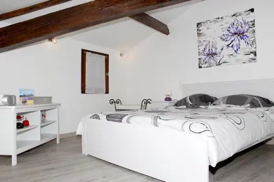 a white bedroom with a large white bed in a room at Gite les coquelicots ( classé 2* ) Duplex in LʼIsle-sur-la-Sorgue