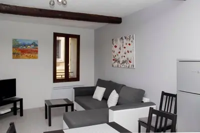 a living room with a gray couch and a window at Gite les coquelicots ( classé 2* ) Duplex in LʼIsle-sur-la-Sorgue
