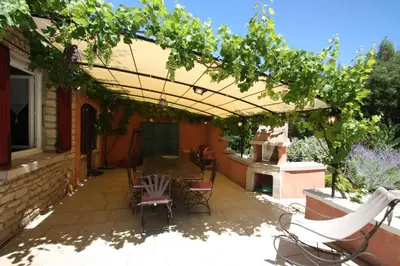 a patio with a table and chairs under a pergola at Lou Cigalon in Cabrières-dʼAvignon