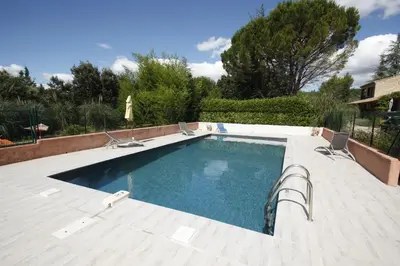 a swimming pool on a patio with two chairs at Lou Cigalon in Cabrières-dʼAvignon