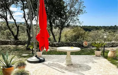 a red umbrella and a table in a garden at Nice Home In Venasque With Kitchen in Venasque