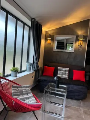 a living room with a couch and a red chair at L'AMANDERAIE PISCINE PRIVEE à côté de LOURMARIN LUBERON in Cadenet