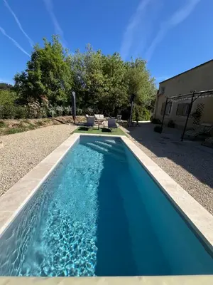 a swimming pool with blue water in a yard at L'AMANDERAIE PISCINE PRIVEE à côté de LOURMARIN LUBERON in Cadenet