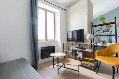 a living room with a tv and a chair and a table at L'Isle en Blanc - 4 couchages - Hypercentre - Clim - Wifi in LʼIsle-sur-la-Sorgue