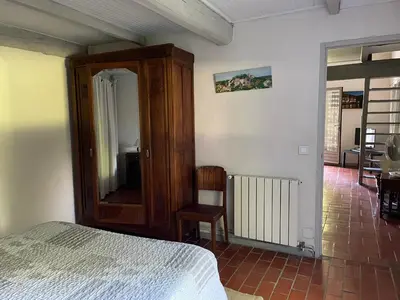 a bedroom with a bed and a mirror and a chair at Mas Grimaud - Gîte- Studio et chambres d'hôtes familiales in Eygalières