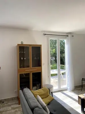 a living room with a couch and a sliding glass door at Charmante Maison au pied du Luberon in Cheval-Blanc