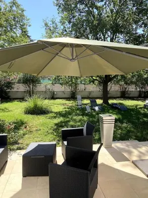 a patio with an umbrella and chairs and tables at Charmante Maison au pied du Luberon in Cheval-Blanc