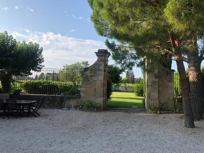 a gate to a garden with a table and a tree at Auberge de Mazan in Mazan