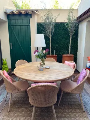 a wooden table with chairs and a green door at La RENAUDIERE in LʼIsle-sur-la-Sorgue