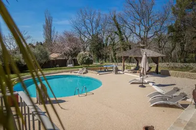 a swimming pool with chairs and a gazebo at El Sama-In , Piscine chauffée in LʼIsle-sur-la-Sorgue
