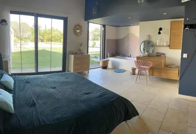 a bedroom with a bed and a bathroom with a tub at Villa avec Pool House au cœur des vignes - Lubéron in La Tour-dʼAigues