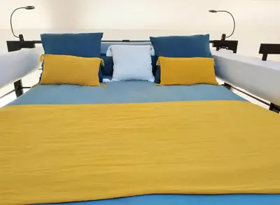 a bed with yellow and blue pillows on it at Grand studio lumineux au calme, centre historique in Pertuis
