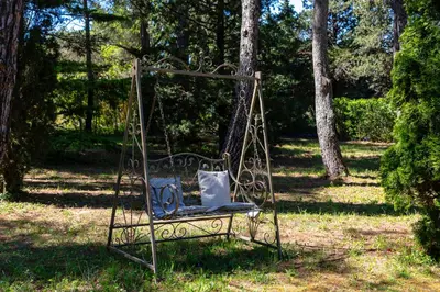 a swing chair with a pillow sitting in the grass at VillaOustal. Parc Arboré 4500 m2. Piscine chauffée. in Carpentras