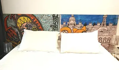 a bed with white pillows and a wall with a mural at Studio centre historique derrière rue d'Italie - Climatisé in Aix-en-Provence