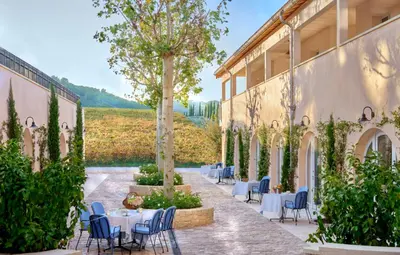 a courtyard with tables and chairs and a tree at Auberge La Coste in Le Puy-Sainte-Réparade