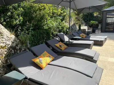 a group of lounge chairs with umbrellas on a patio at Villa en Provence, Spa & piscine, pour 9 personnes- Gîtes les Estelles in Cavaillon