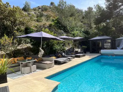 a swimming pool with couches and umbrellas next to a swimming pool at Villa en Provence, Spa & piscine, pour 9 personnes- Gîtes les Estelles in Cavaillon