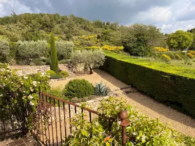 a gate in a garden with bushes and trees at La Paradisse – exceptional Provençal farmhouse (18th century) in Blauvac