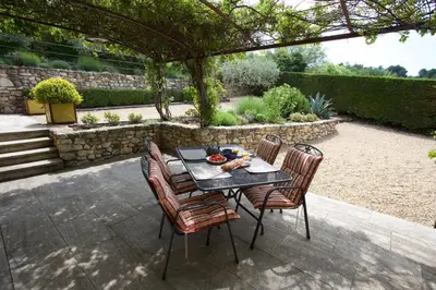 a table and chairs under a pergola in a garden at La Paradisse – exceptional Provençal farmhouse (18th century) in Blauvac