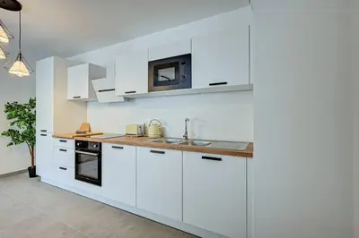 a white kitchen with white cabinets and a microwave at Sublime Appartement 6 couchages avec Parking (Aix-en-Provence) in Aix-en-Provence