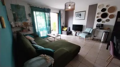 a living room with a green couch and a tv at L'ETOURNEAU in Bédoin