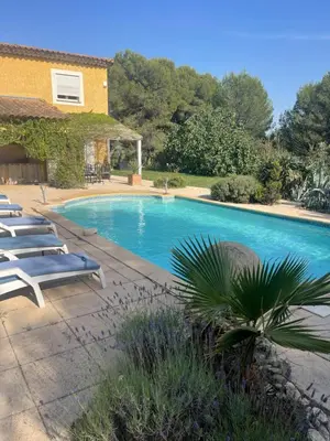 a swimming pool with lounge chairs next to a house at Villa provençale 8 personnes in Ventabren