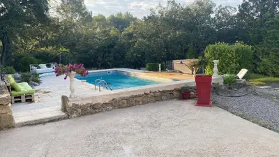 a swimming pool in a yard with a stone wall at La studette provençale in Jouques