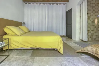 a bedroom with a bed with a yellow blanket on it at Le Mas des Anges in Cabannes